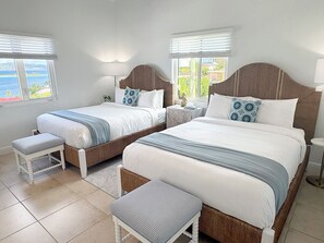 Une chambre d’hôtel avec deux lits, une table de chevet, une petite table et un banc.