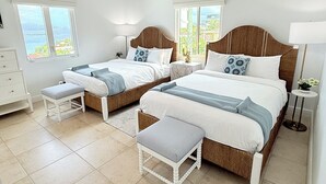 A bedroom with two beds, a nightstand, a dresser, and a window with a view. - Experience the exquisite Mango Serenity, a spacious condo that offers breathtaking views and an abundance of comfort.  Discover your perfect getaway today! (St John)