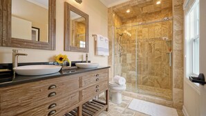 Un bagno con un mobile vanitario in legno, due lavandini, un ampio specchio e una cabina doccia in vetro.