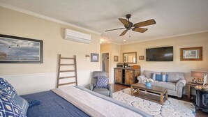 Una camera da letto con un letto, una poltrona, un tavolino in legno, un divano, una televisione e una ventola a soffitto.