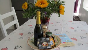 Ett matbord med en flaska champagne, en burk te och en bukett med solrosor.