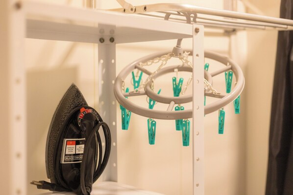 A white metal rack with a circular hanging organizer and a black plastic bag with a label.