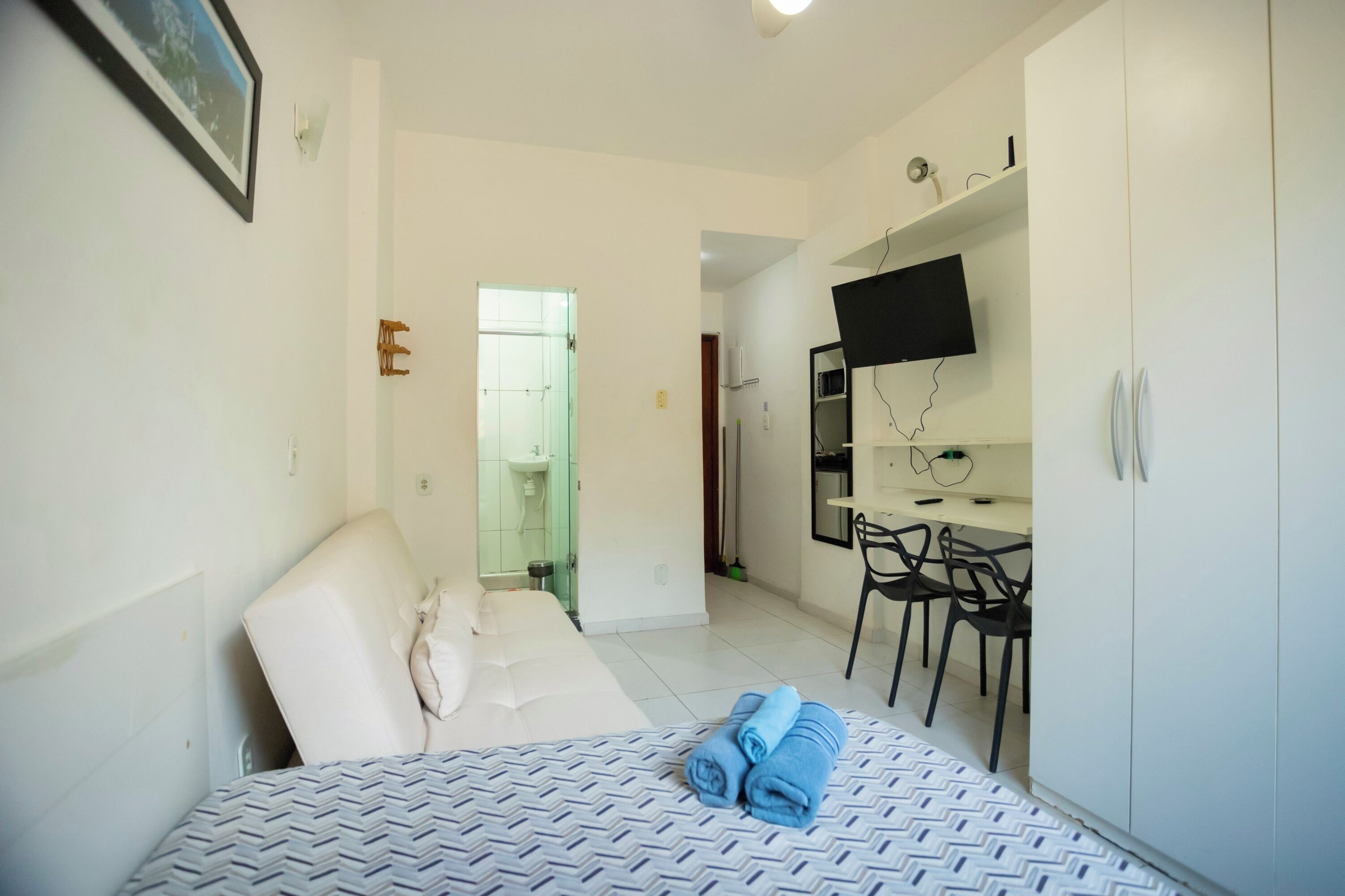 A hotel room with a bed, a desk, a chair, and a television.