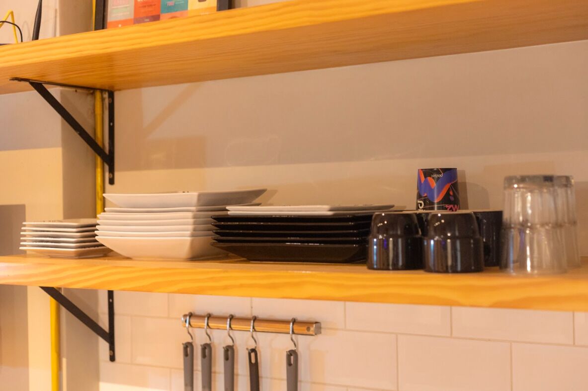 A kitchen shelf with stacked plates, a box, and jars.