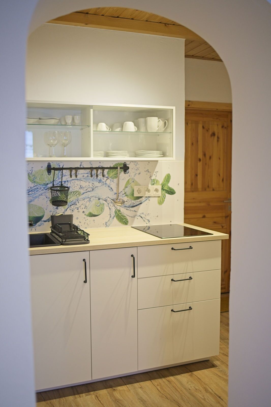 Una cocina con armarios blancos, una encimera y un salpicadero con diseño de salpicadura de agua.