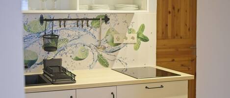 Una cocina con armarios blancos, una encimera y un salpicadero con diseño de salpicadura de agua.