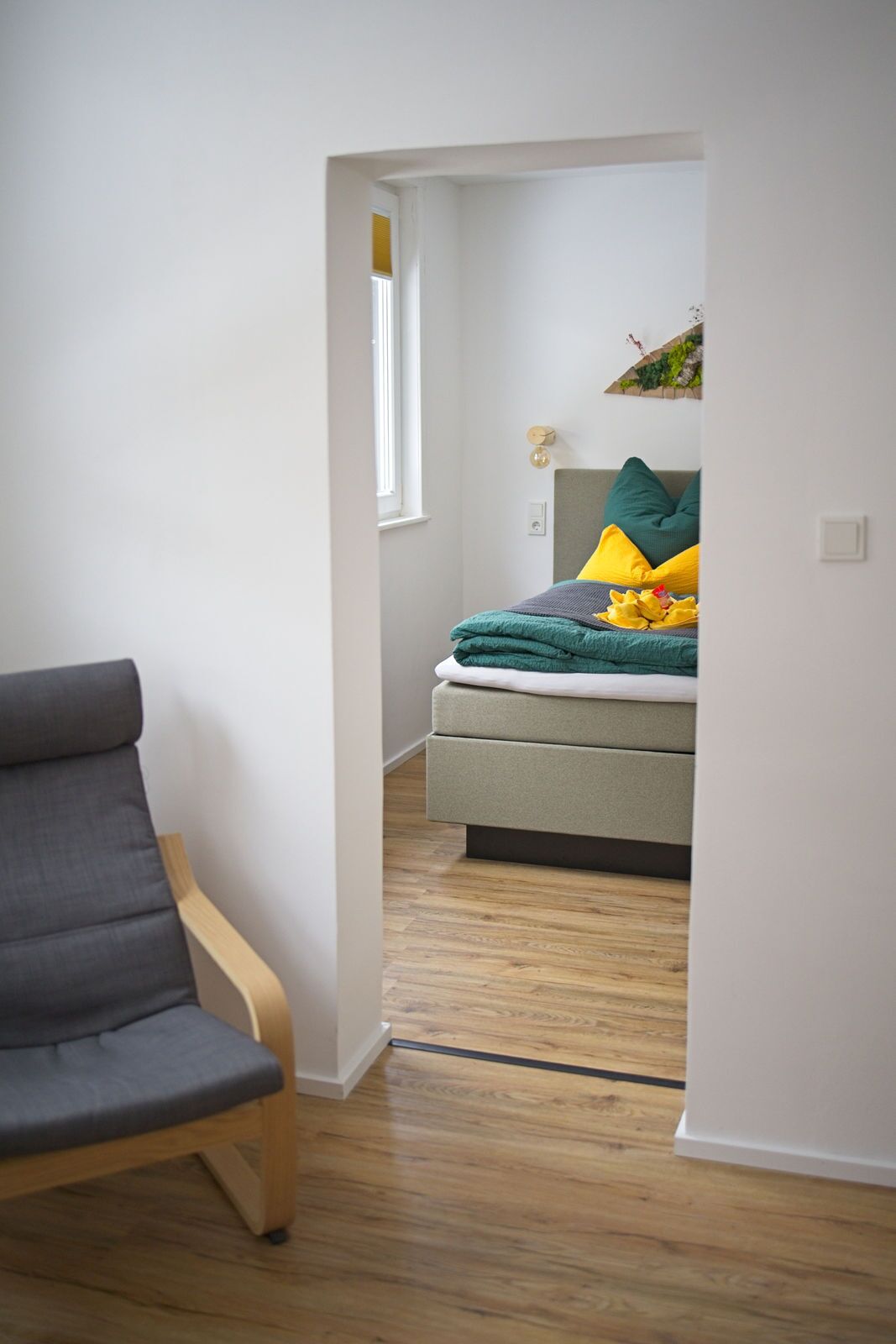 A bedroom with a bed, a chair, and a window.