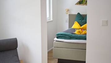 Ein Schlafzimmer mit Bett, Stuhl und Fenster.