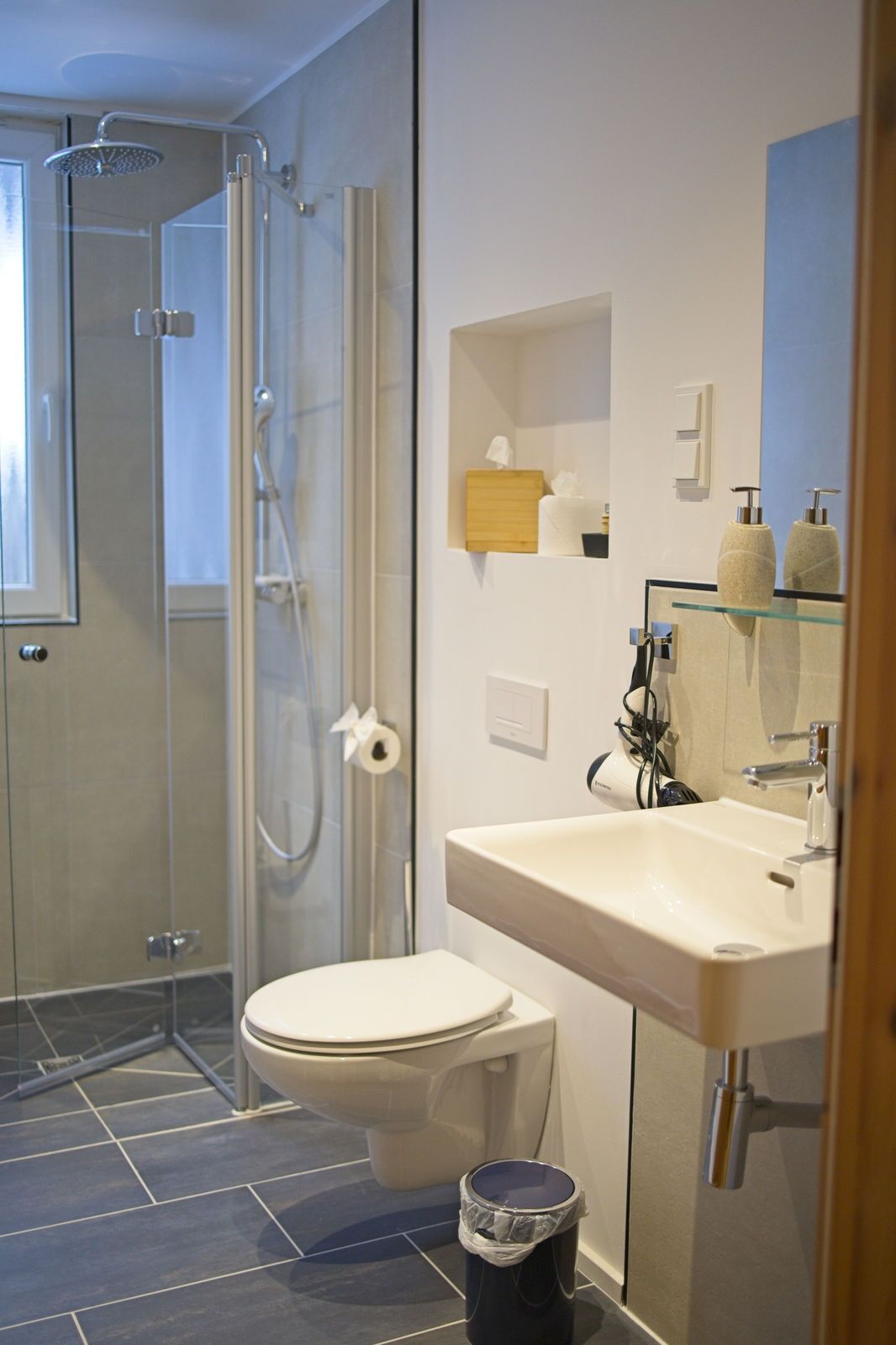 A modern bathroom with a glass shower enclosure, a toilet, a sink, and a mirror.