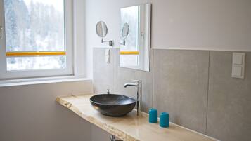 A bathroom with a large window, a black basin, two mirrors, and two blue soap dispensers.
