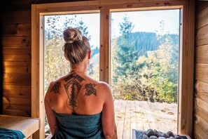 A person with a tattoo on their back, standing in a room with wooden walls and a large window. - Haus RAuszeit (Clausthal-Zellerfeld)