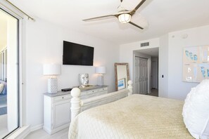 A bedroom with a bed, a ceiling fan, a dresser, a mirror, and a TV on the wall. - Coastal Beachfront Condo w/ Beach Service Included in Destin! 🏖🐚 (Destin)