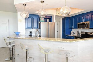 Una cocina moderna con armarios azules, electrodomésticos de acero inoxidable y una zona de bar con taburetes.