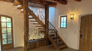 A wooden staircase with a wrought iron railing, a wooden door, and a small window with a light fixture.