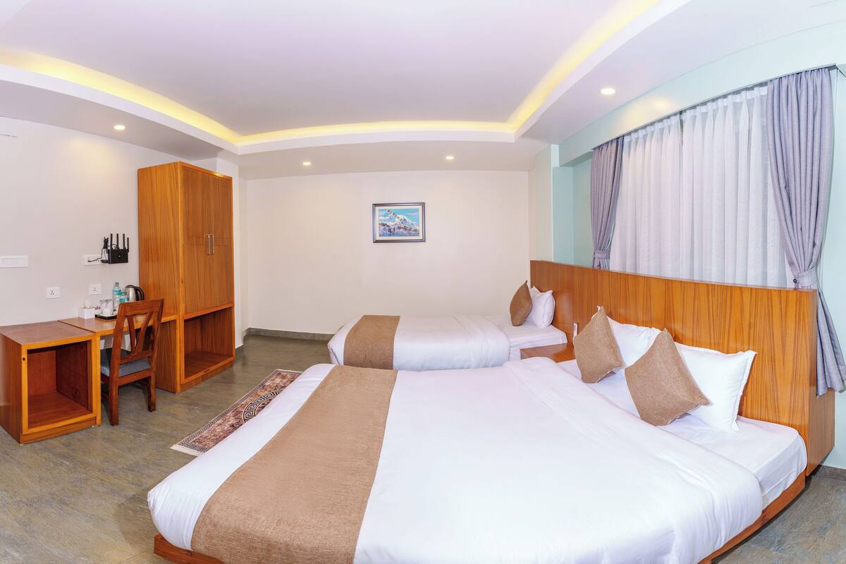 A hotel room with two beds, a desk, and a wardrobe.
