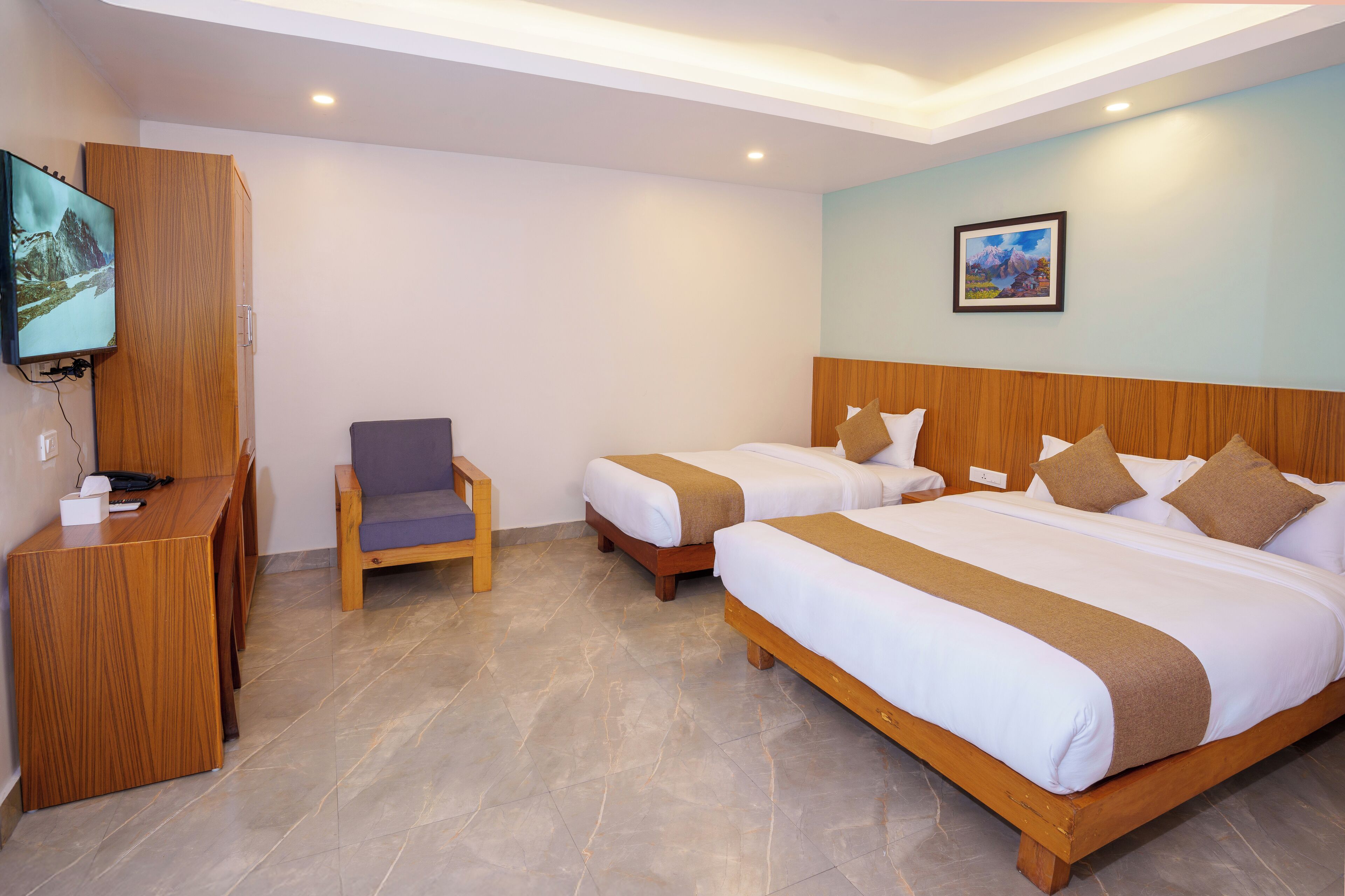 Habitación de hotel con dos camas, un escritorio, una silla y un televisor montado en un mueble de madera.