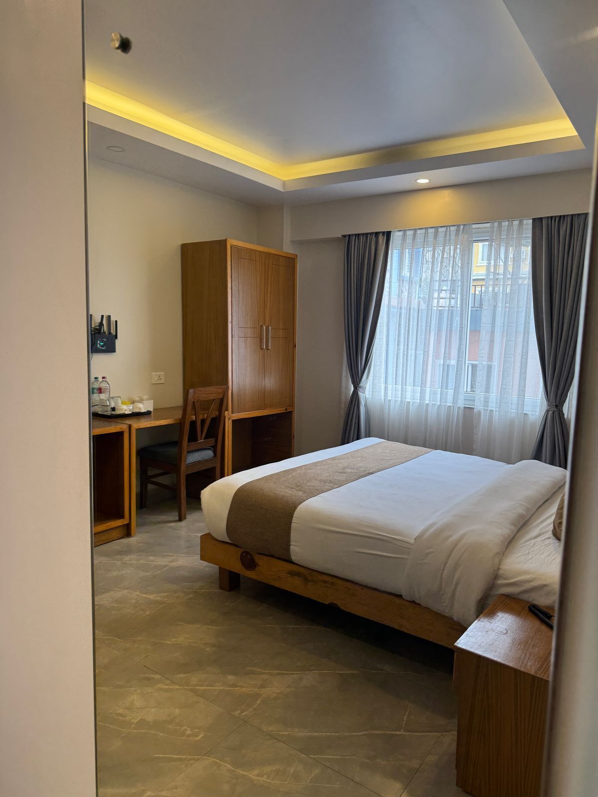 Un dormitorio moderno con una cama grande, un armario de madera, un escritorio y una silla.