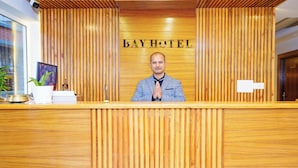 A hotel reception desk with a wooden panel design and the name "BAY HOTEL" displayed above. - Bay Hotel (Pokhara)