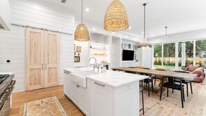 Una cocina moderna con armarios blancos, una isla central e iluminación colgante.