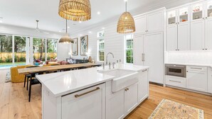 Una cocina moderna con armarios blancos, una isla grande e iluminación colgante.
