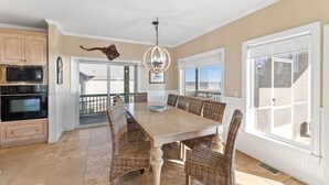A spacious kitchen with a dining area, featuring a large table, wicker chairs, and a chandelier. - Gulf Front Home with Pool | Hot Tub (Port St Joe)