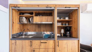 A compact kitchen with wooden cabinets, a stainless steel sink, and a coffee maker. - Beachfront Sunny Penthouse - Kalamata SeaBliss (Kalamata)