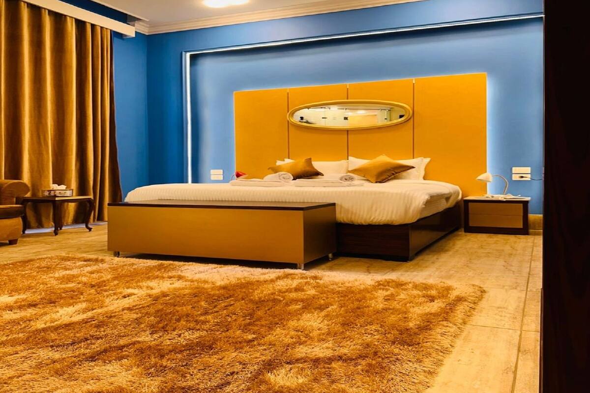 A modern bedroom with a large bed, a fluffy rug, and a nightstand.