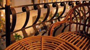 A wicker chair with a metal frame, a building with illuminated windows, and a railing. - GA PLUS (Cairo)