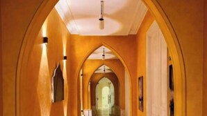 A long, arched hallway with a bench, a door at the end, and a light fixture on the ceiling. - GA PLUS (Cairo)