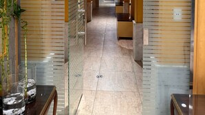 A modern hallway with glass partitions, a central archway, and a tiled floor. - GA PLUS (Cairo)