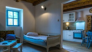 Une petite pièce agréable et confortable, avec un lit simple, une table et une chaise. Elle comprend un coin cuisine équipé d’une cuisinière et de placards.