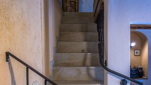Un escalier avec une rampe en métal et des marches en pierre menant à une pièce dont le plafond est en bois.