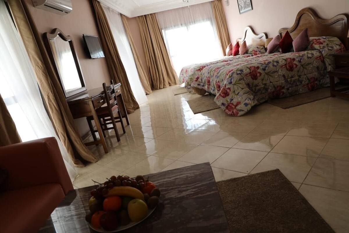 Een hotelkamer met een bed, een bureau, een stoel en een schaal fruit.