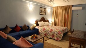 Una sala de estar acogedora con un sofá azul, un edredón estampado y una mesita con fruta fresca.