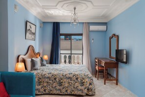 Une chambre avec un lit, un bureau, une télévision et un balcon donnant sur une vue agréable.