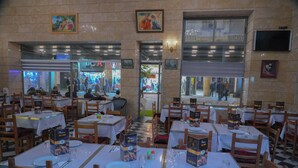 Un restaurante con varias mesas y sillas, suelo a cuadros y cuadros en las paredes.