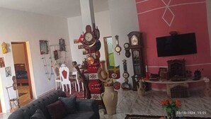 A living room with a sofa, a TV, and various clocks on the wall. - Villa Atlas Osis (As-Sabikah)