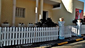 A building with a white picket fence, columns, and potted plants. - Villa Atlas Osis (As-Sabikah)