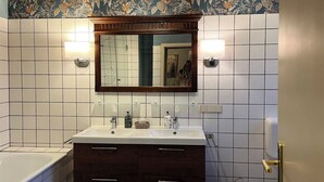 Un baño con dos lavamanos, un espejo grande y una bañera.