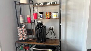 Un área de cocina con cafetera, microondas y refrigerador compacto.