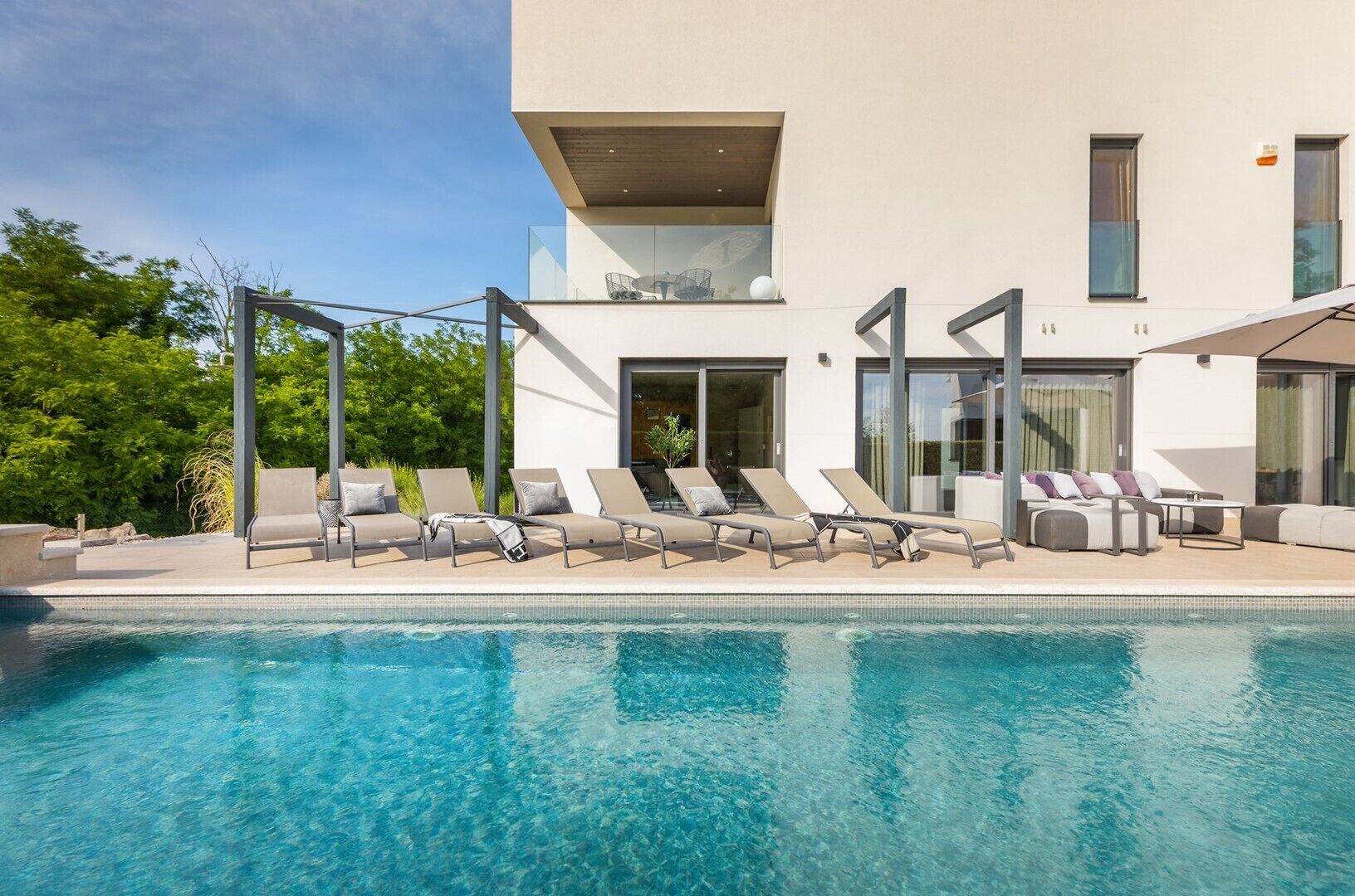Ein moderner Poolbereich mit Liegestühlen und einem klaren, blauen Pool.