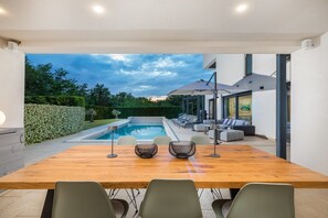 A modern outdoor dining area with a pool, seating, and a view of the sky. - Villa Luce Verde - beautiful villa with private pool, hot tub and sauna near the town of Porec and its beaches (Kirmenjak)