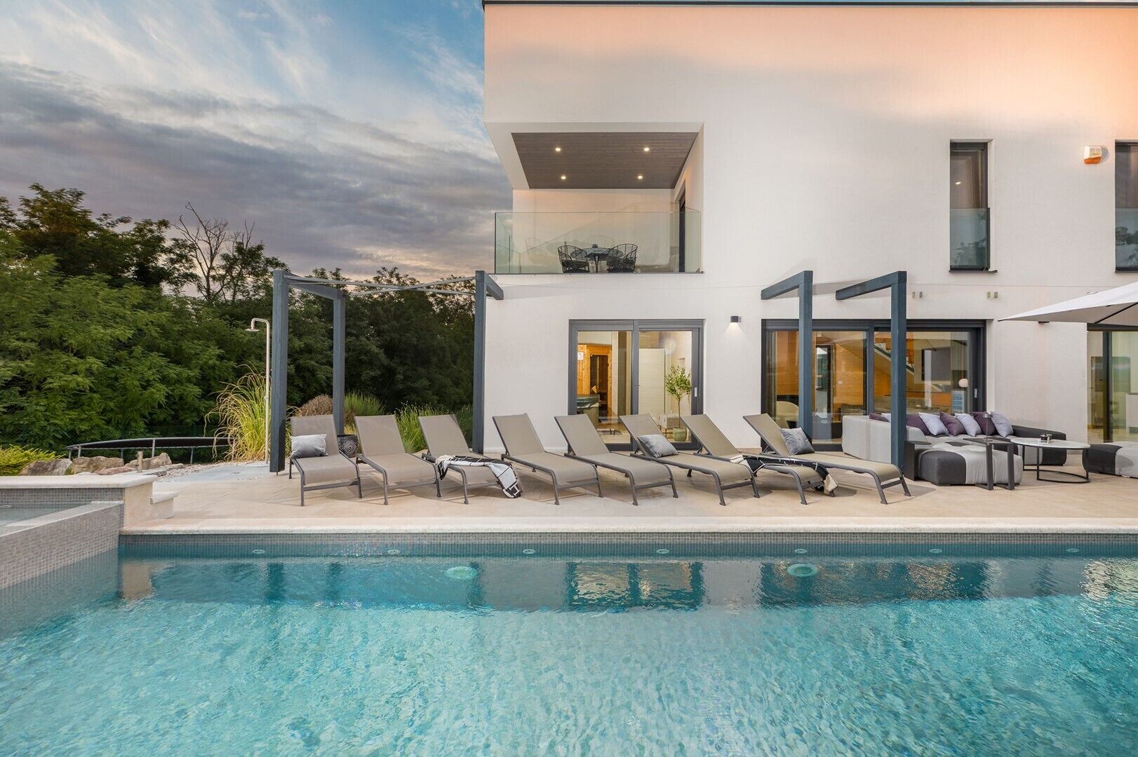 Un área de piscina moderna con sillones de descanso y una piscina cristalina.