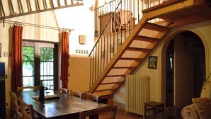 Un coin repas avec une table et des chaises en bois, un escalier et un radiateur.