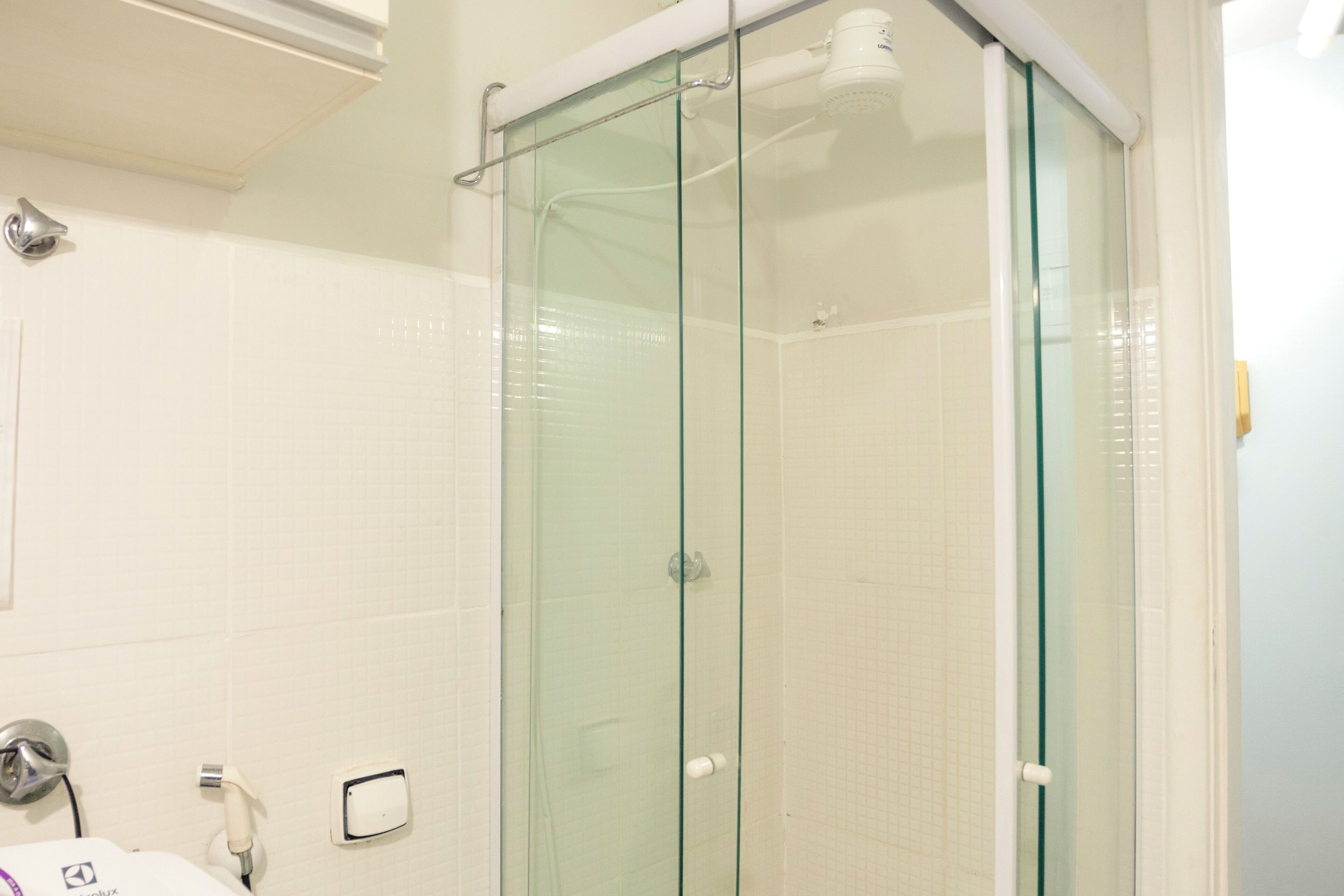 A bathroom with a glass shower enclosure, a white sink, and a mirror.
