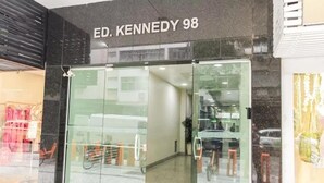 Ingresso di un edificio con un cartello che riporta la scritta 'ED. KENNEDY 98'.