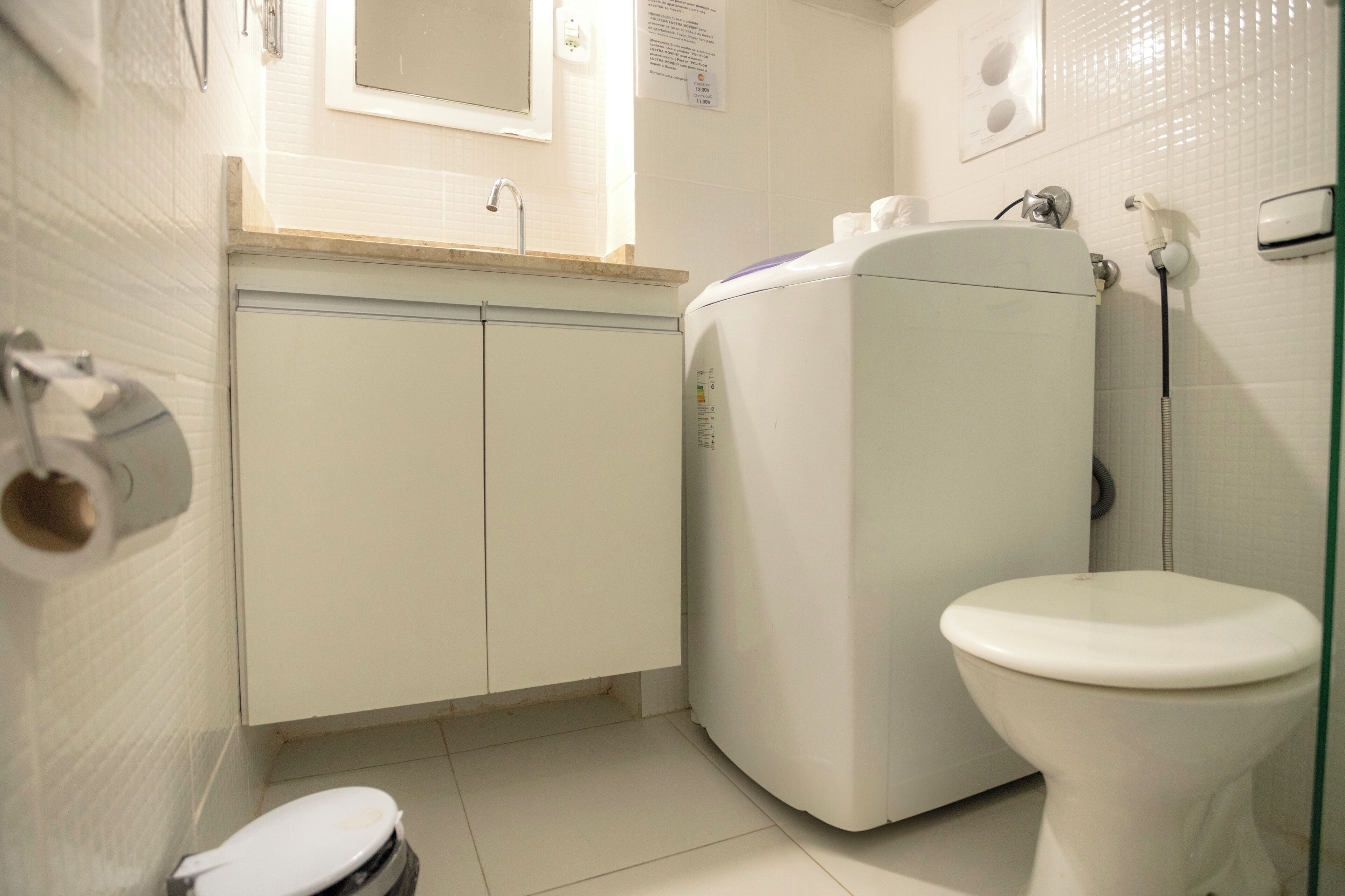 Une petite salle de bain propre, équipée de toilettes, d’un lave-linge et d’un lavabo.