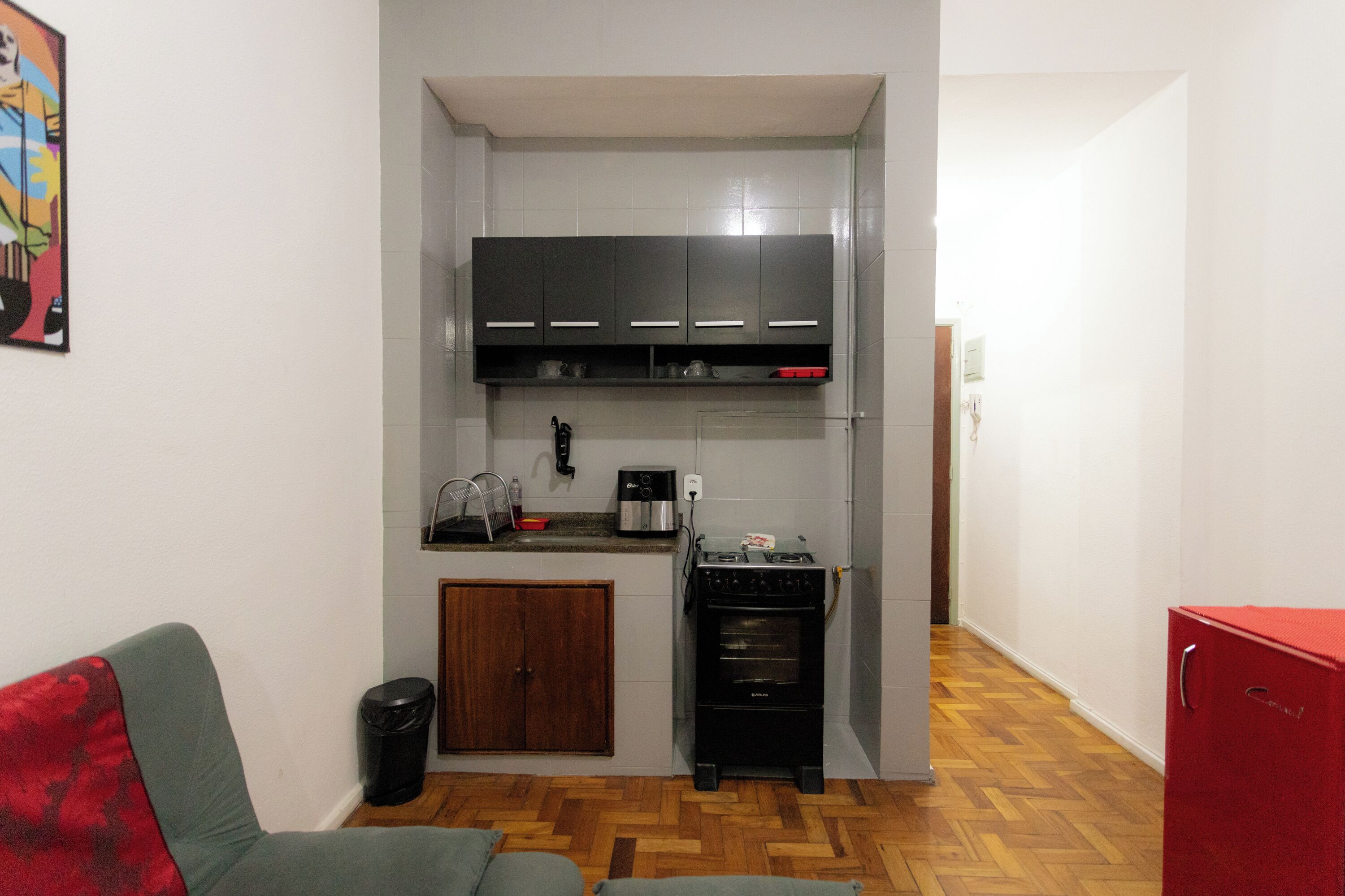 A compact kitchen with a built-in oven, a coffee maker, and a red refrigerator.