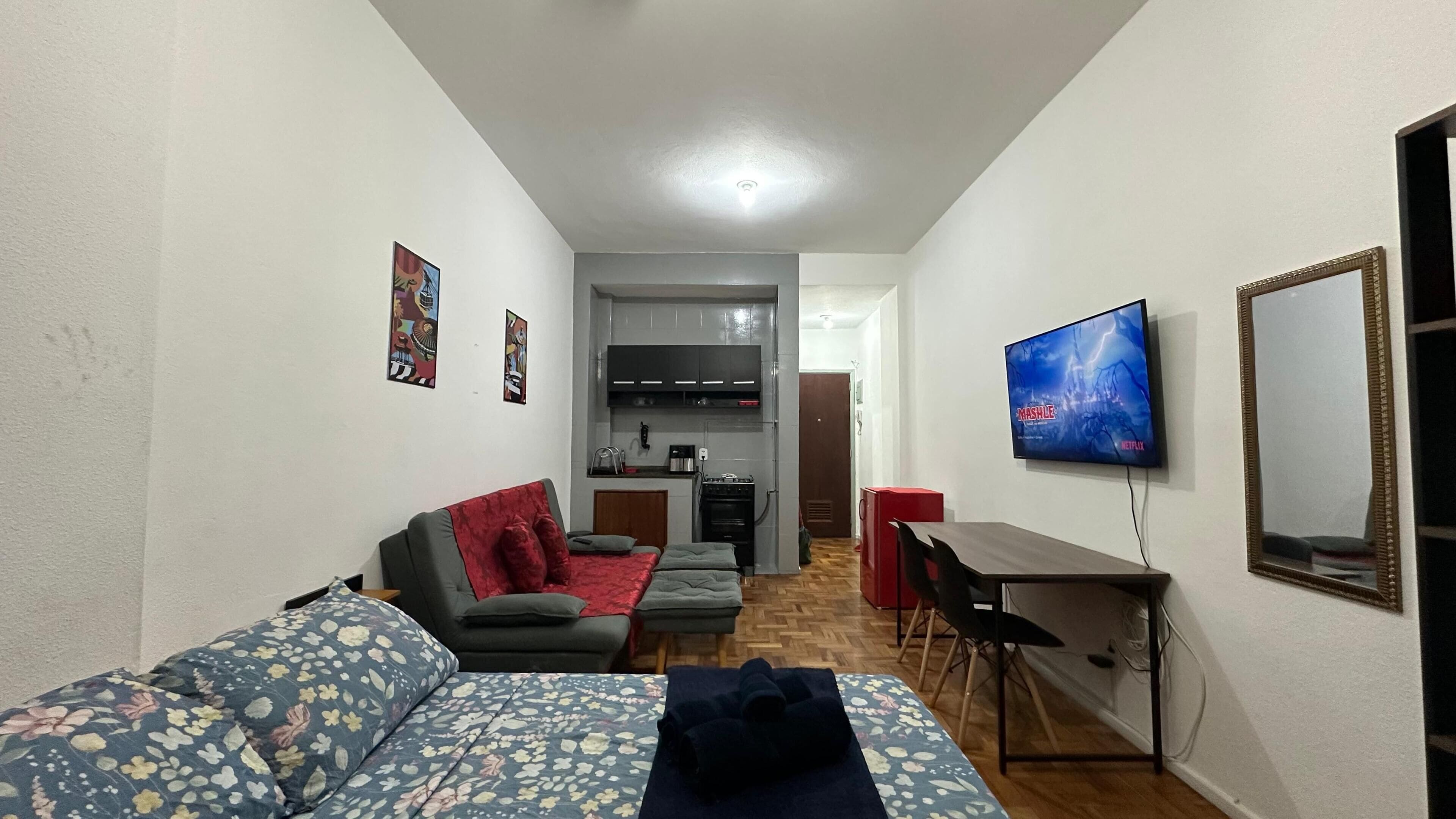 Een knus woongedeelte met een bank, een eettafeltje, een televisie en een kitchenette.