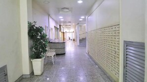 Un corridoio con una reception, una pianta in vaso e una fila di armadietti lungo la parete destra.